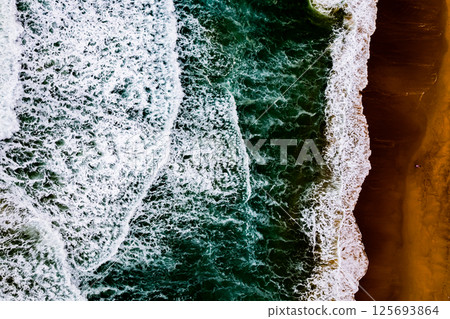 Top view Dark waves crashing on sandy shore beach background,Amazing waves sea nature background 125693864