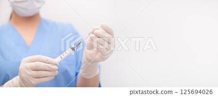 nurse draws medicine from an ampoule into a syringe 125694026
