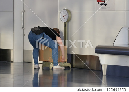Passengers on an international flight having their checked baggage weighed. Passengers in the international lobby at Haneda Airport. 125694253