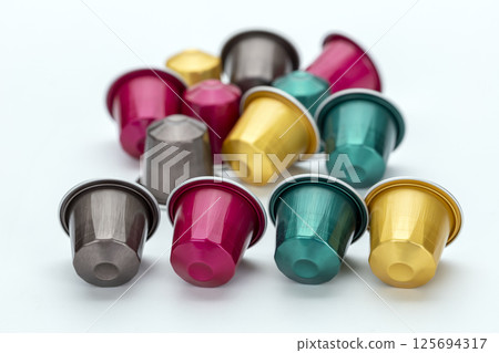 Colorful coffee capsules scattered on white background, featuring various vibrant hues like pink, gold, teal, and silver. arrangement creates lively and dynamic composition Colorful coffee capsules scattered on white background, featuring various vibrant hues like pink, gold, teal, and silver. arrangement creates lively and dynamic composition 125694317