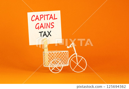 Capital gains tax symbol. Concept words Capital gains tax on beautiful white paper on wooden clothespin. Beautiful orange background. Business and capital gains tax concept. Copy space. 125694362