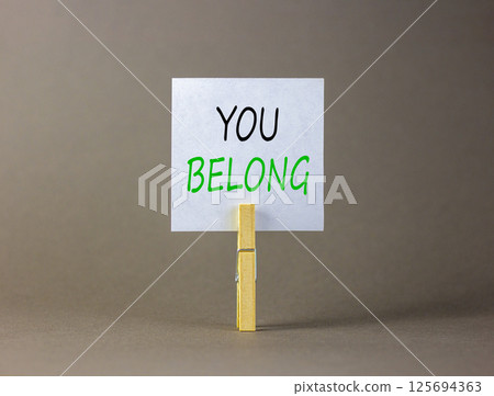 Belonging and you belong symbol. Concept words You belong on beautiful white paper on wooden clothespin. Beautiful grey background. Business belonging and you belong concept. Copy space. 125694363