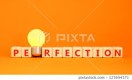 Perfection symbol. Concept word Perfection on beautiful wooden blocks. Beautiful orange table orange background. Yellow light bulb. Business perfection concept. Copy space. Perfection symbol. Concept word Perfection on beautiful wooden blocks. Beautiful orange table orange background. Yellow light bulb. Business perfection concept. Copy space. 125694371