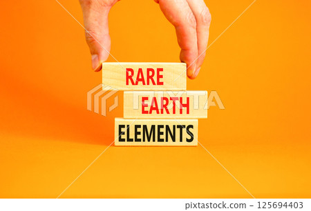 Rare earth elements symbol. Concept words Rare earth elements on beautiful wooden block. Businessman's hand. Beautiful orange background. Business and rare earth elements concept. Copy space. 125694403