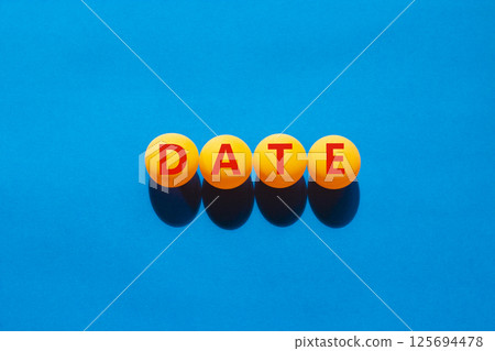 Date symbol. Concept word Date on beautiful yellow ping pong balls. Beautiful blue table blue background. Business and date concept. Copy space. Date symbol. Concept word Date on beautiful yellow ping pong balls. Beautiful blue table blue background. Business and date concept. Copy space. 125694478