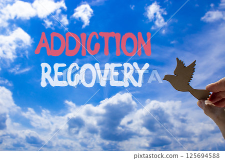 Addiction recovery symbol. Concept words Addiction recovery on beautiful blue sky. Psychologist hand, wooden bird. Beautiful blue sky cloud background. Psychology addiction recovery concept Copy space Addiction recovery symbol. Concept words Addiction recovery on beautiful blue sky. Psychologist hand, wooden bird. Beautiful blue sky cloud background. Psychology addiction recovery concept Copy space 125694588