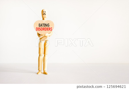 Eating disorders symbol. Concept words Eating disorders on beautiful wooden heart. Doctor's model. Beautiful white background. Copy space. Medical healthy lifestyle eating disorders concept. Eating disorders symbol. Concept words Eating disorders on beautiful wooden heart. Doctor's model. Beautiful white background. Copy space. Medical healthy lifestyle eating disorders concept. 125694621