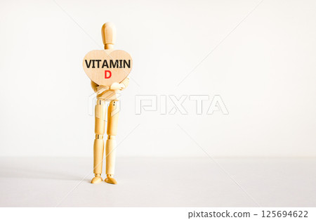 Vitamin D symbol. Concept words Vitamin D on beautiful wooden heart. Doctor's model. Beautiful white background. Copy space. Medical healthy lifestyle Vitamin D concept. Vitamin D symbol. Concept words Vitamin D on beautiful wooden heart. Doctor's model. Beautiful white background. Copy space. Medical healthy lifestyle Vitamin D concept. 125694622