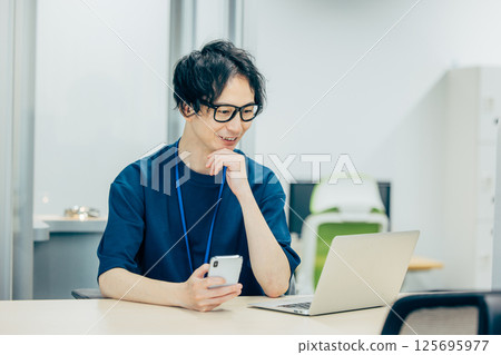 A businessman who looks at a smartphone and thinks 125695977