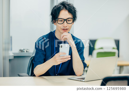 A businessman who looks at a smartphone and thinks 125695980