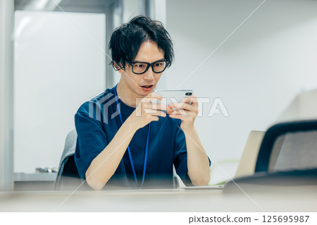 A man playing a smartphone game at work 125695987