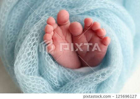 Baby foot on blue soft coverlet, blanket. Close-up of tiny, cute, bare toes, heels and feet of a newborn girl, boy. Baby foot on blue soft coverlet, blanket. Close-up of tiny, cute, bare toes, heels and feet of a newborn girl, boy. 125696127