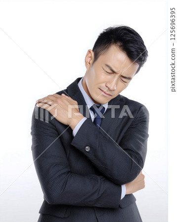 A middle-aged Japanese male businessman in a suit suffering from stiff shoulders. White background 125696395