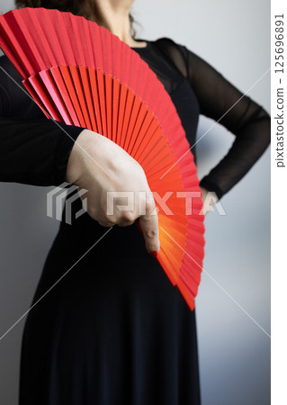 Woman holding red fan in black dress 125696891