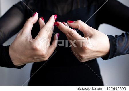 Female adult caucasian hands performing dance gesture with red nails in black outfit Female adult caucasian hands performing dance gesture with red nails in black outfit 125696893