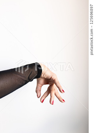 Female hand with red nails in black sheer sleeve on white background Female hand with red nails in black sheer sleeve on white background 125696897