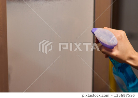 Cleaning a glass surface effectively with a spray bottle to achieve a clear, shiny finish Cleaning a glass surface effectively with a spray bottle to achieve a clear, shiny finish 125697556