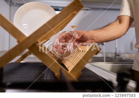 Carefully hand placing a clean, sparkling dish into the drying rack for organization and hygiene 125697583