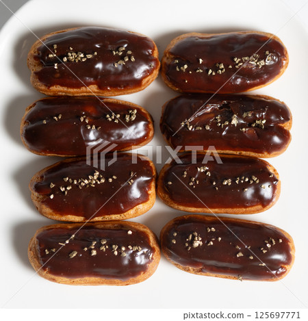 Eight classic eclairs arranged neatly on a white plate. Eight classic eclairs arranged neatly on a white plate. 125697771