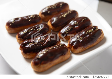 Eight classic eclairs arranged neatly on a white plate. 125697772