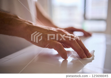 A person is meticulously hand cleaning a surface using a cloth in a bright and inviting environment 125698045