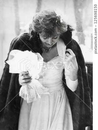 Vintage portrait of a bride in snowy weather. The girl looks down to avoid slipping. Retro photo from 1993. 125698150