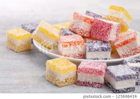 Cubes of multi-colored marmalade in powdered sugar on plate. The concept of baby sweets. 125698439