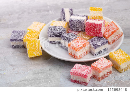 Cubes of multi-colored marmalade in powdered sugar on plate. The concept of baby sweets. 125698448