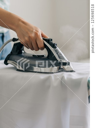 Housewife ironing white t shirt on ironing board 125698518