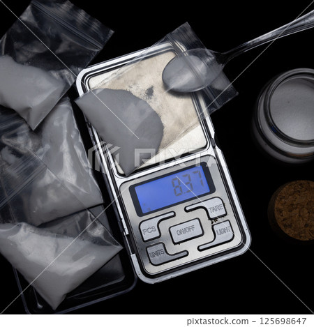 On a tabletop digital scale a bag of white powder. concept drug sale 125698647