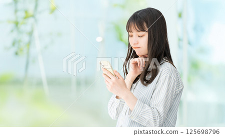 女人/女商人一邊看著智慧型手機一邊思考 女人/女商人一邊看著智慧型手機一邊思考 125698796