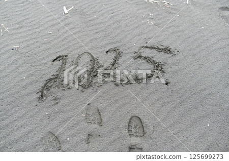 2025 written on wet sand with footprints nearby, concept of new year and future 2025 written on wet sand with footprints nearby, concept of new year and future 125699273