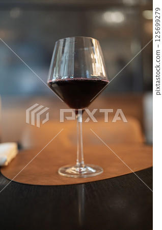 Glass of red wine resting on restaurant table Glass of red wine resting on restaurant table 125699279