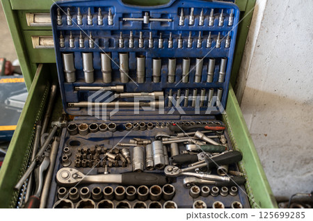 Socket wrench set with various bits and tools in an open green tool drawer 125699285