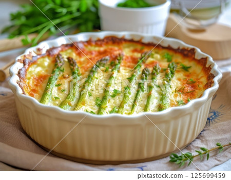 A delicious creamy asparagus bake, perfectly browned and garnished with fresh herbs, is served in a rustic-style baking dish A delicious creamy asparagus bake, perfectly browned and garnished with fresh herbs, is served in a rustic-style baking dish 125699459
