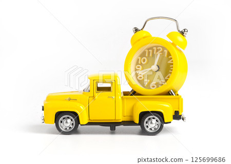 A yellow alarm clock in a toy truck. White background with copy space for text. Deadline and the concept of timeliness 125699686