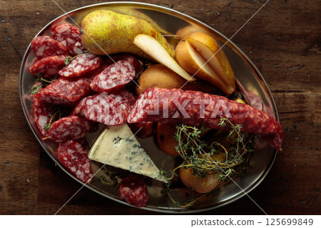 Dry-cured sausages, blue cheese, thyme and pears. 125699849