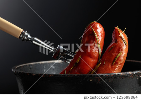 Roasted Bavarian sausages with rosemary in an old black pan. Roasted Bavarian sausages with rosemary in an old black pan. 125699864