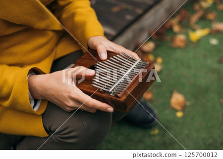 close-up woman playing the musical instrument Kalimba or Mbira in the fall on the terrace 125700012