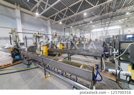 Extrusion lines manufacturing plastic products in contemporary factory Extrusion lines manufacturing plastic products in contemporary factory 125700358
