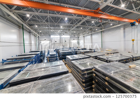 Pvc windows wrapped in stretch film, pallets and overhead crane in distribution warehouse Pvc windows wrapped in stretch film, pallets and overhead crane in distribution warehouse 125700375