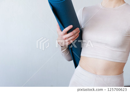 Beautiful girl getting ready for yoga indoors in daylight. Beautiful girl getting ready for yoga indoors in daylight. 125700623