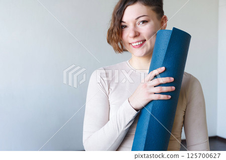 Beautiful girl getting ready for yoga indoors in daylight. 125700627