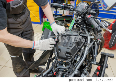The master performs maintenance on the motorcycle. 125700668