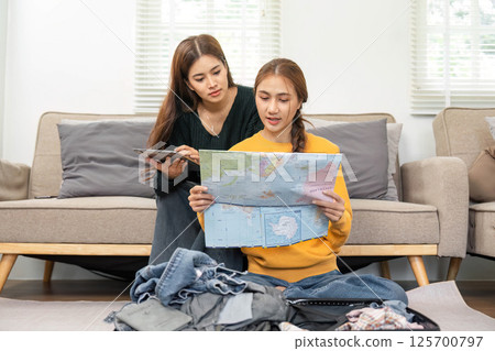 Exciting travel planning: Friends analyzing maps and packing Exciting travel planning: Friends analyzing maps and packing 125700797