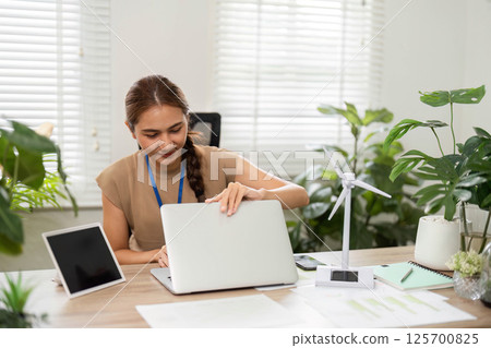 ESG Sustainability focus with woman working on laptop in green office 125700825