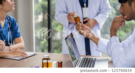 Doctor holding medication while consulting with a colleague 125700834