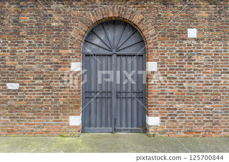 Arched Iron Gate in Brick Wall Facade Arched Iron Gate in Brick Wall Facade 125700844