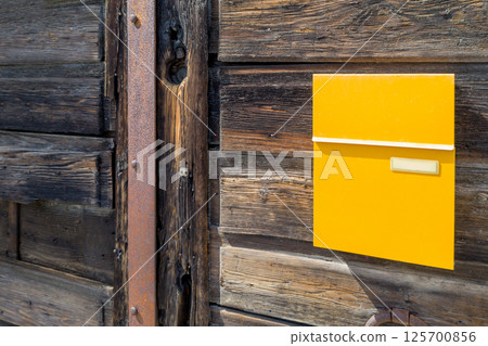 Bright Yellow Mailbox on Rustic Wooden Wall Bright Yellow Mailbox on Rustic Wooden Wall 125700856
