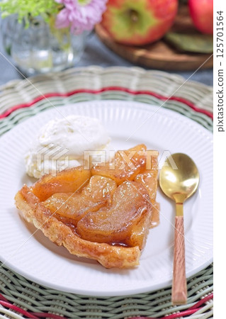 Slice of delicious apple tarte tatin with scoop of whipped cream, french upside down cake, vertical 125701564